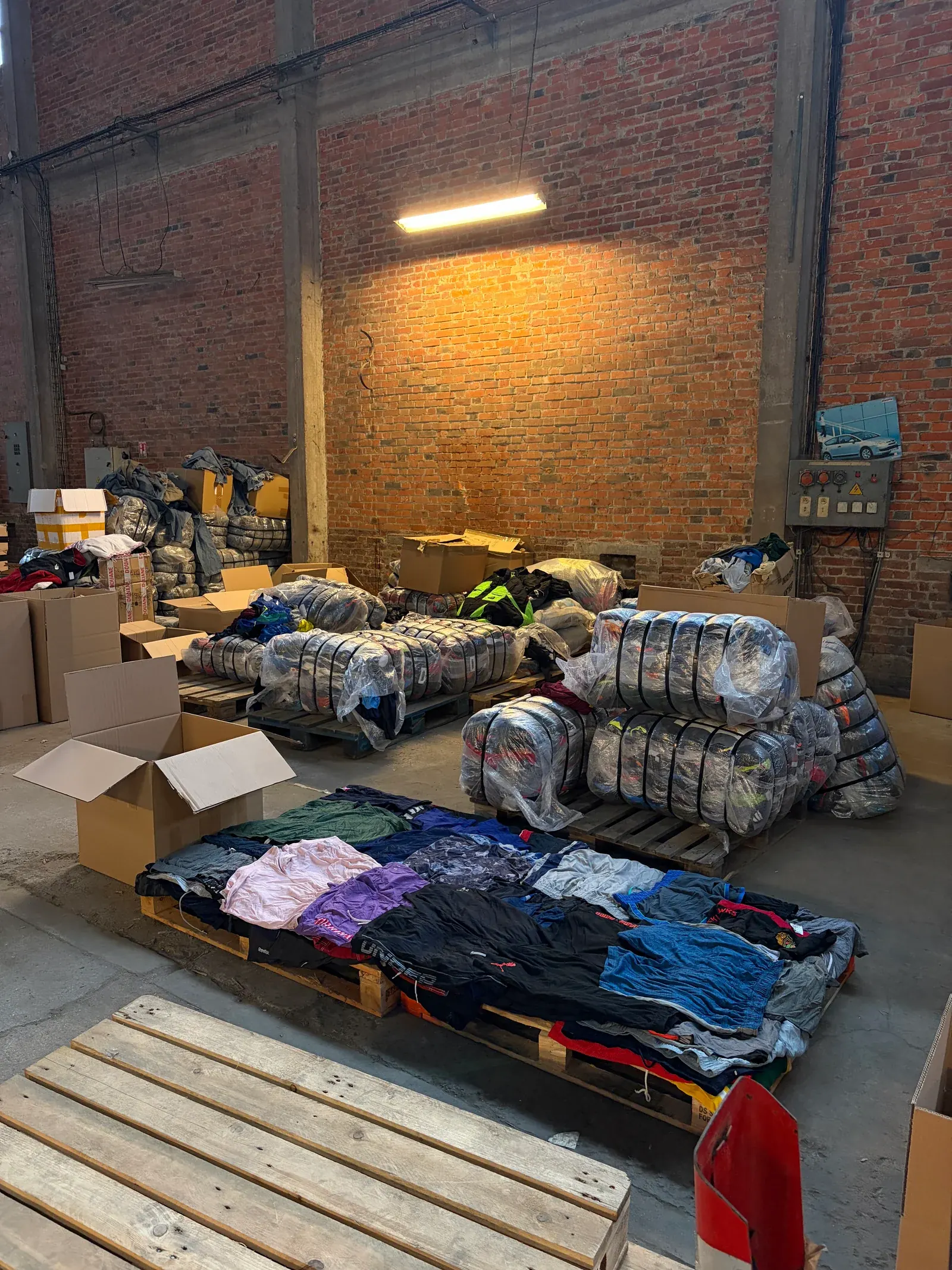 Balles de vêtements ouvertes et shorts de sport triés sur une palette dans l'entrepôt Wholesaler 2.0