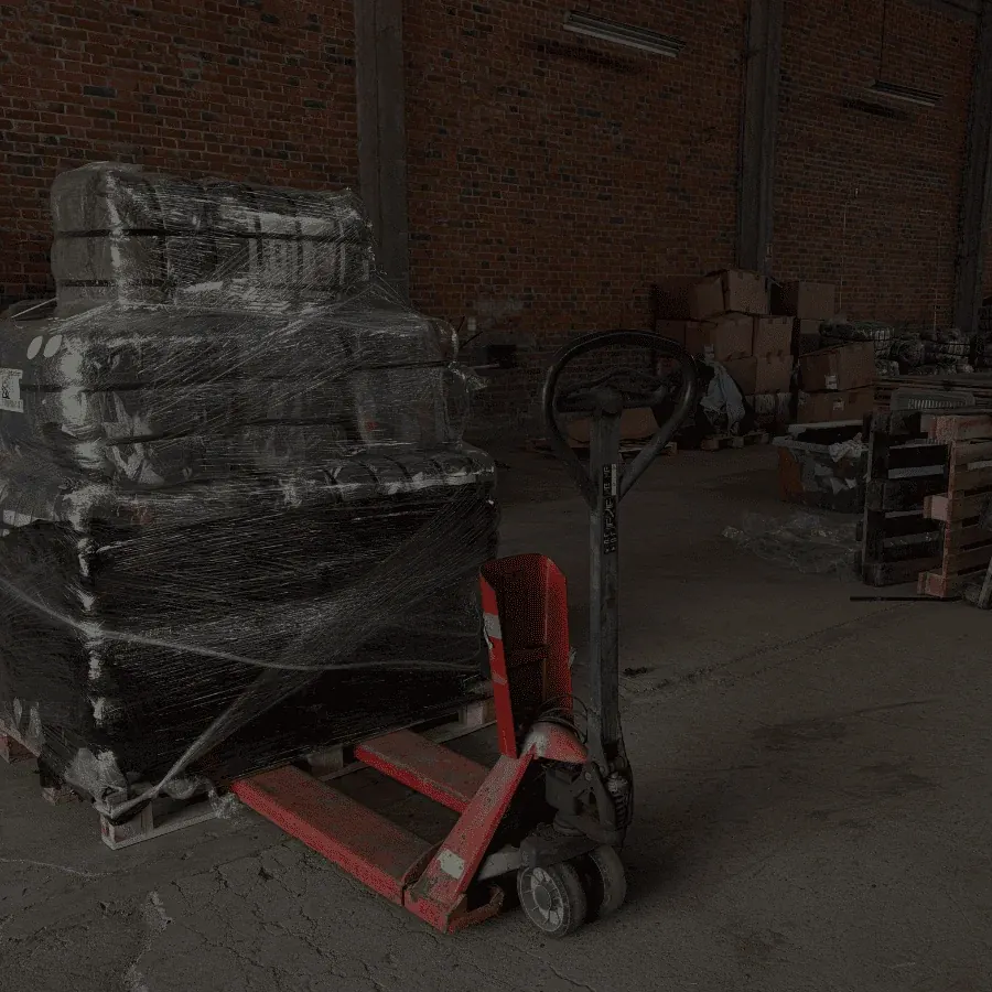 Palette de balles de vêtements filmée et transpalette rouge dans l'entrepôt Wholesaler 2.0