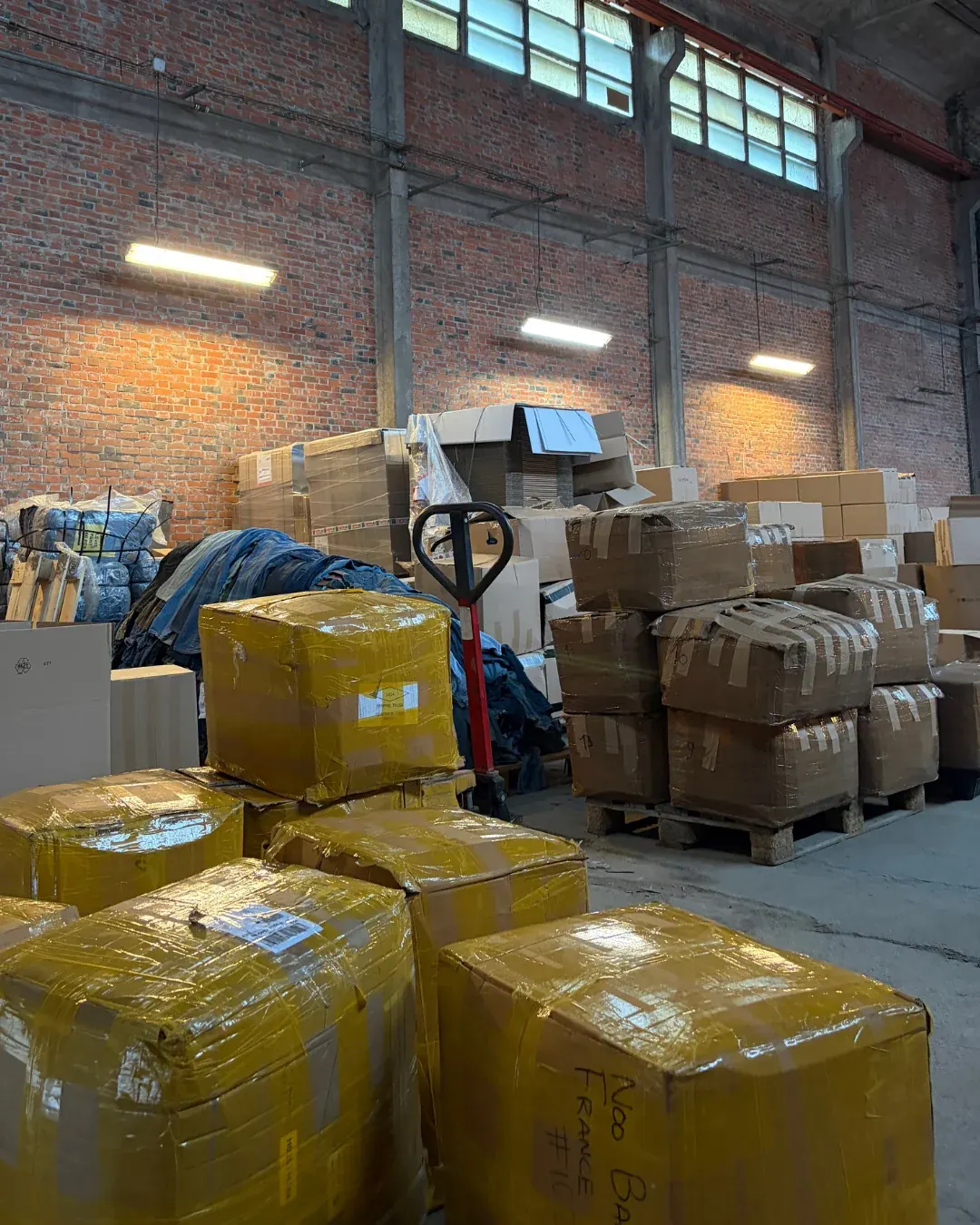 Cartons filmés, ballots de jeans et palettes de colis avec transpalette dans l'entrepôt Wholesaler 2.0